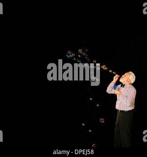 Studio shot of senior woman blowing bubbles Banque D'Images