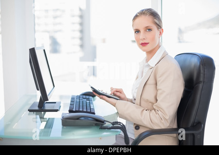 Vue latérale du blond businesswoman using calculator Banque D'Images