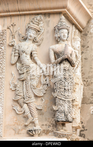 Sculptures en pierre des femmes priant au mur du temple en Thailande Banque D'Images