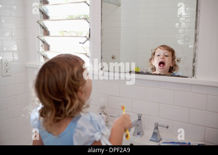 Female toddler à nettoyer les dents en miroir Banque D'Images