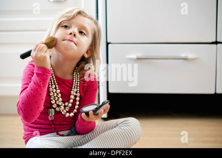 Jeune fille assise sur le plancher de la cuisine avec de Banque D'Images