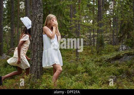 Adolescentes joue à cache-cache dans la forêt Banque D'Images