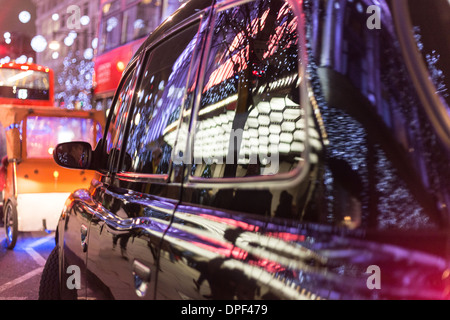 Réflexions de lumières de Noël dans un taxi londonien noir coincé dans le trafic sur Oxford Street Banque D'Images