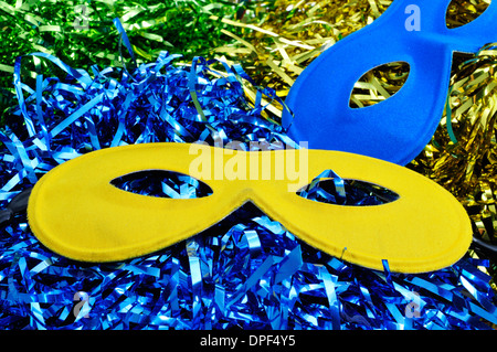 Une paire de masques de carnaval de couleurs différentes sur un arrière-plan avec les guirlandes de couleurs différentes Banque D'Images