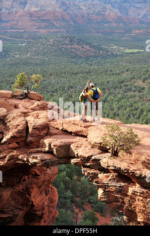 Couple de randonnée affichage à partir de fenêtres cintrées rock formation, Sedona, Arizona, USA Banque D'Images