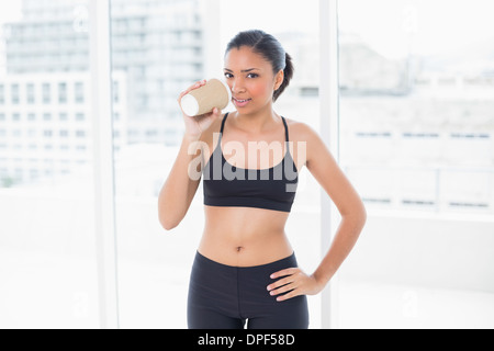 Pensive dark haired model in sportswear drinking coffee Banque D'Images