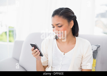 Jeune femme aux cheveux noirs en blanc à la recherche de son téléphone portable Banque D'Images