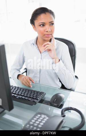 Pensive young dark haired businesswoman looking away Banque D'Images