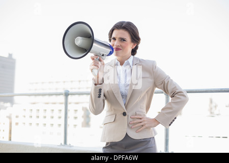 Fronçant brun élégant businesswoman holding a megaphone Banque D'Images