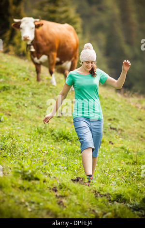 Femme marche à travers champ de vache Banque D'Images