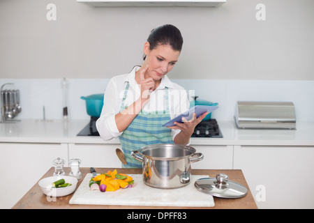 L'accent gorgeous woman wearing apron using tablet Banque D'Images