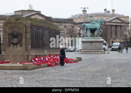 Une dame se penche sur le Cénotaphe de Liverpool sur Dimanche du souvenir, 2013. Les couronnes ont été déposées plus tôt ce jour au cours d'un service. Banque D'Images