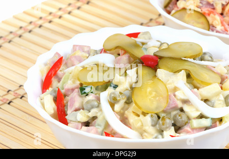 Salade d'hiver Olivier dans un plat blanc sur un fond de serviette en bambou Banque D'Images