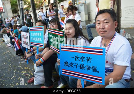 Les Chinois de souche des manifestants anti-gouvernement s'asseoir sur un trottoir dans le centre de Bangkok holding signes contre le gouvernement du pays Banque D'Images