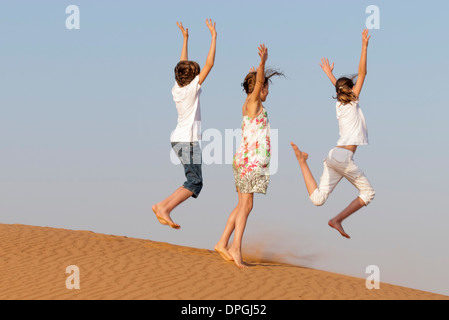 Les enfants sauter sur le sable, vue arrière Banque D'Images