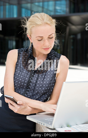 Businesswoman using laptop working outdoors Banque D'Images