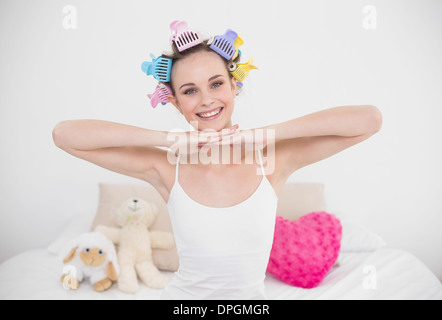 Joyful natural brown haired woman in hair curlers posing looking at camera Banque D'Images