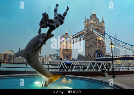 Le Tower Bridge et la statue d'une jeune fille jouant avec dauphin en St Katharine Docks de Londres. Banque D'Images