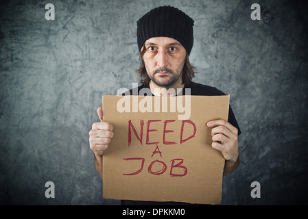 Man holding carton papier avec besoin d'un message de la tâche. La recherche d'emploi, problèmes de chômage. Banque D'Images