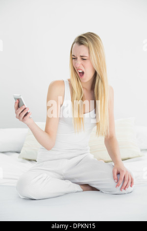 Belle blonde woman choqué à son smartphone Banque D'Images