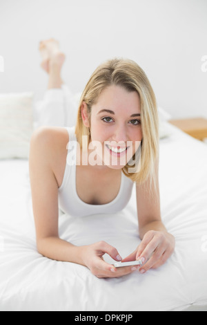 Jolie femme en utilisant son smartphone smiling at camera Banque D'Images