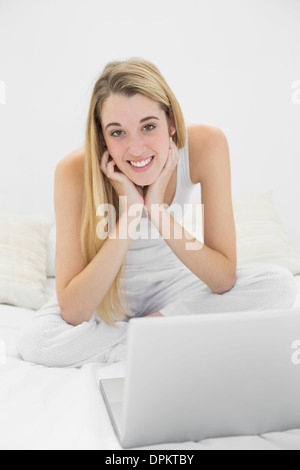 Content blonde woman smiling at camera while using her notebook Banque D'Images