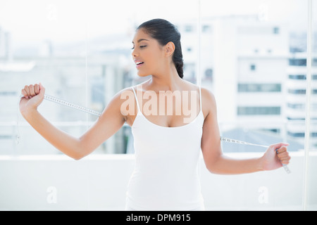 Plaisir tonique brunette holding measuring tape derrière retour Banque D'Images