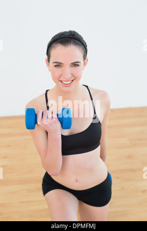 Femme souriante avec haltère au studio de remise en forme Banque D'Images