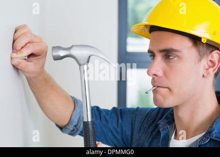 Handyman hammering nail à wall Banque D'Images