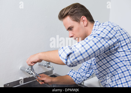 Plombier sérieux d'un robinet d'eau avec une pince de fixation Banque D'Images