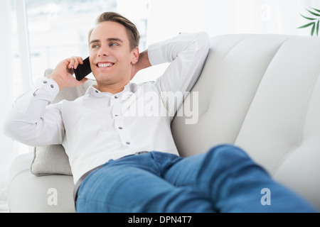 Homme détendue using cellphone while lying on sofa Banque D'Images