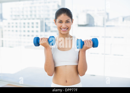 Woman exercising with dumbbells in fitness studio Banque D'Images