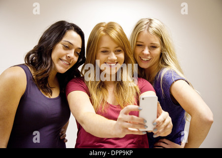 Trois happy smiling teen girls prendre un sur un iPhone d'apple selfies Essex, UK Banque D'Images