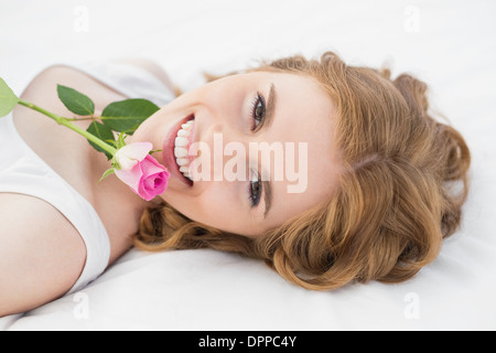 Pretty young woman resting in bed with rose Banque D'Images