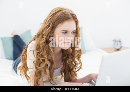 Casual young blonde using laptop in bed Banque D'Images