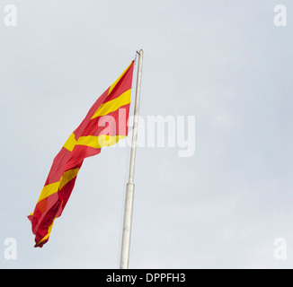 En agitant le drapeau macédonien sur un mât contre le ciel bleu Banque D'Images