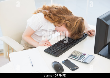 Businesswoman resting head sur clavier at office Banque D'Images