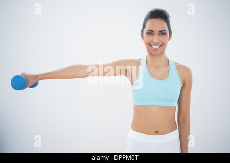 Slender dark haired woman lifting dumbbell bleu Banque D'Images