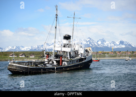 L'épave du Saint Christopher (HMS) La justice est échoué dans le port d'Ushuaia, Argentine. La Sain Christopher est un remorqueur de sauvetage intégré qui a servi dans la Marine royale britannique dans la seconde guerre mondiale. Après la guerre, elle a été désaffectée du Royal Nay et vendus pour les opérations de sauvetage dans le canal de Beagle. Après avoir subi les problèmes du moteur en 1954, elle a échoué en 1957 dans le port d'Ushuaia où elle sert maintenant comme monument de la épaves de la région. Les montagnes couvertes de neige dans la distance sont à travers le canal de Beagle au Chili. Banque D'Images