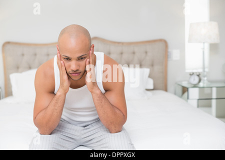 Thoughtful chauve sitting on bed Banque D'Images