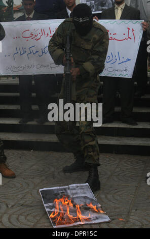 Décembre 16, 2008 - La ville de Gaza, territoire palestinien - des Palestiniens armés de fusil au point une affiche du président américain George W. Bush au cours d'une manifestation organisée par le groupe armé palestinien résistant à l'appui des comités populaires d'un journaliste irakien Muntadar al-Zeidi qui a lancé ses chaussures contre le président américain George W. Bush lors d'une conférence de presse à Bagdad, le dimanche, en criant en Arabe Banque D'Images