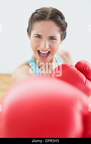 Belle jeune femme en rouge des gants de boxe au studio de remise en forme Banque D'Images