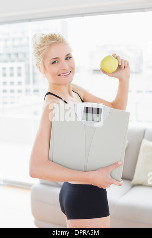 Fit woman Smiling in sportswear holding apple et échelle Banque D'Images