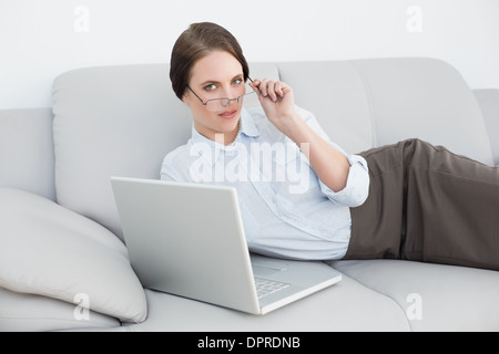 Portrait d'une femme habillés à l'aide de l'ordinateur portable sur canapé Banque D'Images