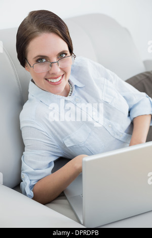 Portrait d'une femme habillés avec ordinateur portable sur canapé Banque D'Images