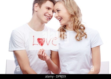 Portrait of young couple smiling girl holding tout en papier avec mot amour Banque D'Images