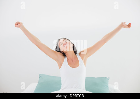 Femme étendant ses bras avec les yeux fermés dans le lit Banque D'Images