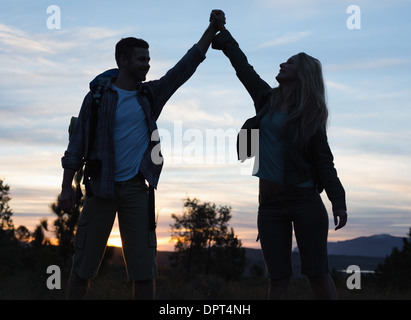 Silhouette couple holding up hands at Dusk Banque D'Images