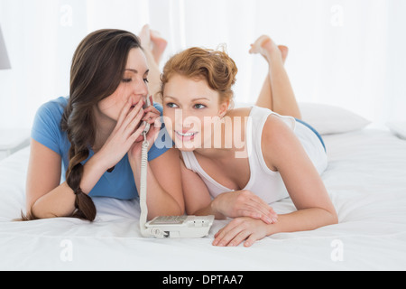 Femme avec un ami à l'aide de téléphone en Lying in Bed Banque D'Images