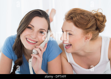 Femme avec l'aide d'ami gai phone in bed Banque D'Images